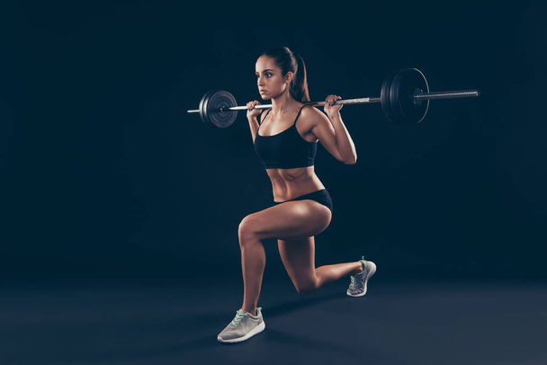 Full length profile photo active short sport suit lady heavy barbell shoulders competition isolated black background - Φωτογραφία, εικόνα