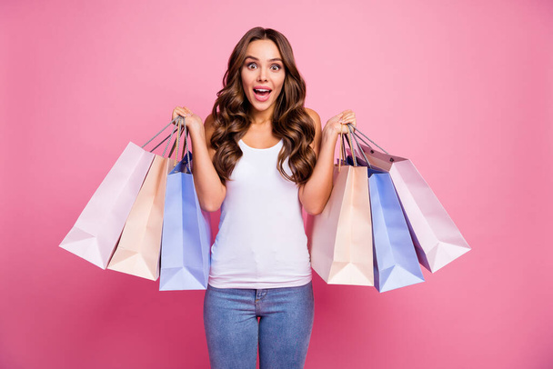 Photo of attractive lady long perfect curly hair amazing mood hold many packs addicted shopper sale prices wear white casual singlet jeans isolated pink color background - 写真・画像