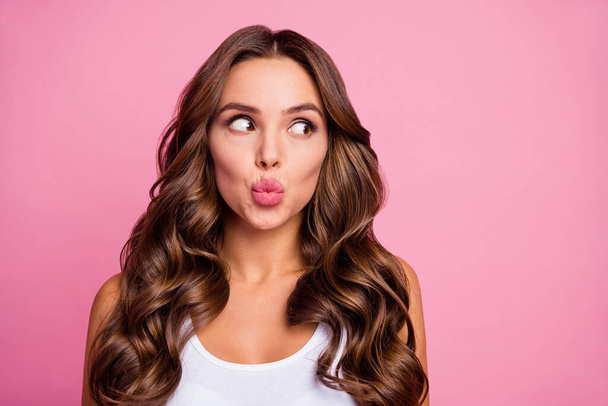 Closeup photo of pretty funny curly lady crazy facial expression sending air kisses look interested side empty space wear white casual singlet isolated bright pink color background - 写真・画像