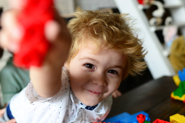 Boy plays with plastic blocks on defocused background - Zdjęcie, obraz