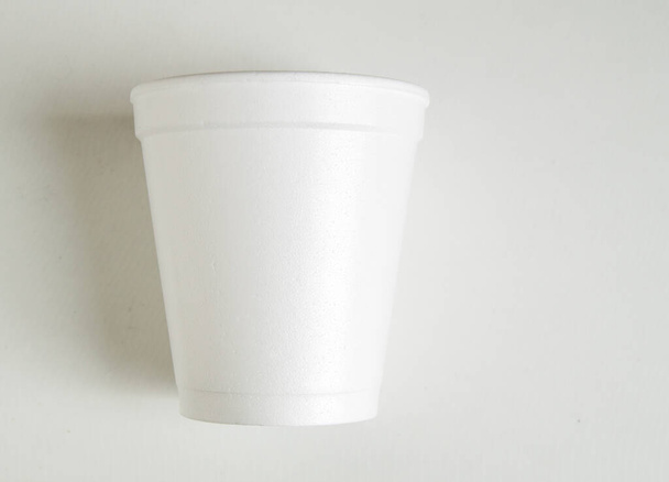 Taza de plástico blanco vacío para bebidas calientes sobre un fondo blanco, minimalismo, copia del espacio. - Foto, Imagen