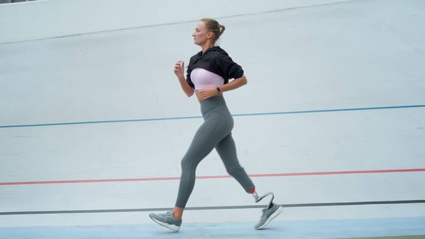 Läufer mit künstlichen Gliedmaßen, die im Freien trainieren. Sportlerin joggt im Stadion - Foto, Bild