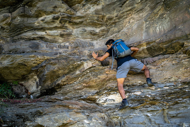 Jonge jongen klimt de rotsen in een rugzak. - Foto, afbeelding