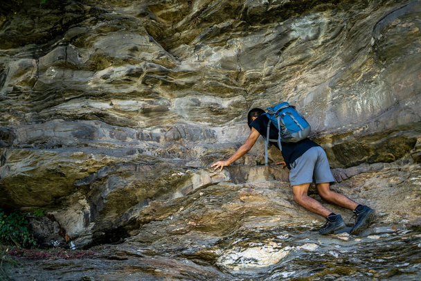 Jeune garçon escalade les rochers portant un sac à dos. - Photo, image