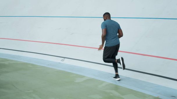 Afro-Läufer beim Training auf der Sportbahn. Sportlicher Mann läuft auf Leichtathletik-Bahn - Foto, Bild