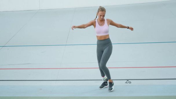 Sportowiec ze sztuczną nogą skaczący bokiem po torze. Szkolenie dziewcząt na stadionie - Zdjęcie, obraz