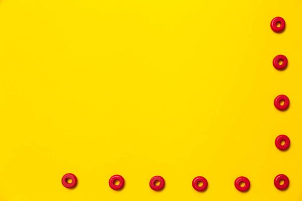 Sobre un fondo amarillo, hay anillos de color rojo del mismo tamaño, que forman un marco en la educación y el desarrollo de los niños. Fondo para colocar texto y otra información. - Foto, imagen