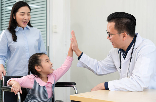 asiático médico jogar alta cinco com jovem que visita no hospital clínica com sua mãe. pediatra e conceito de saúde
 - Foto, Imagem