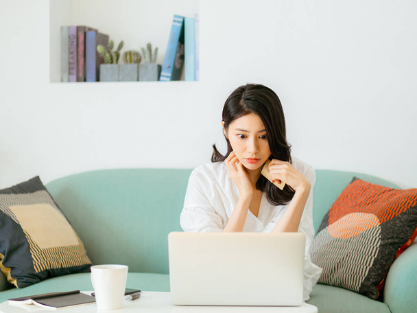 Young woman shopping online with credit card and laptop at home - 写真・画像