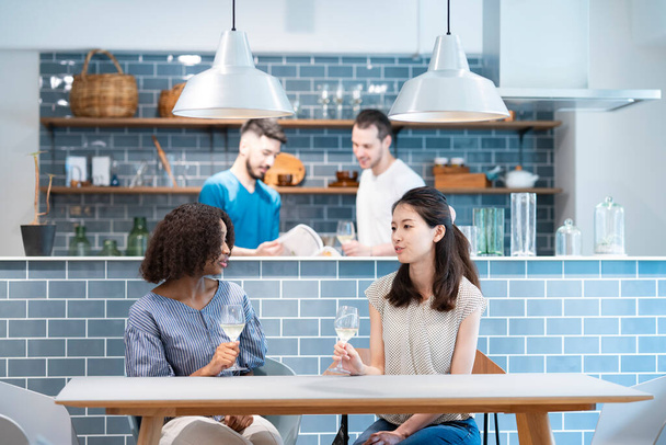 Женщины и мужчины разных рас общаются за обеденным столом - Фото, изображение