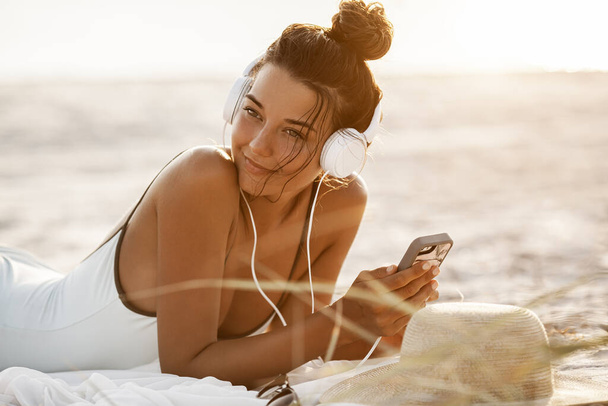 Woman in Bikini with a Smartphone and Headphones on the Beach - Fotografie, Obrázek
