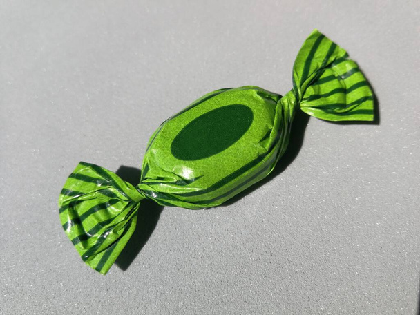 Caramelo envuelto en un paquete que se imprime en dos tonos de verde, imagen - Foto, imagen