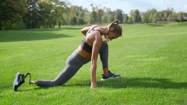 Bezbariérová žena natahuje nohy v parku. Ženský atlet ráno cvičí - Fotografie, Obrázek