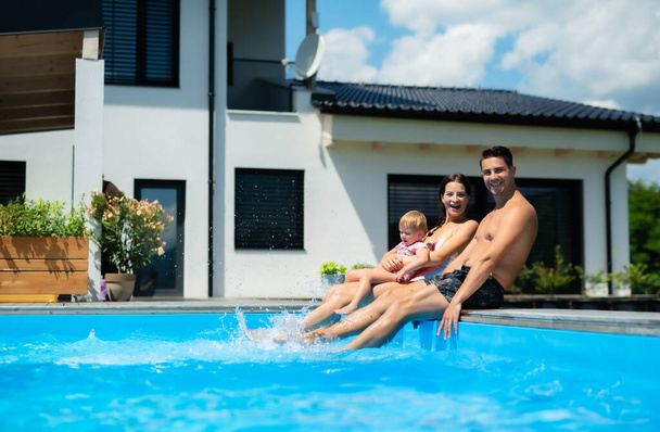 Young family with small daughter in swimming pool outdoors in backyard garden. - Fotografie, Obrázek