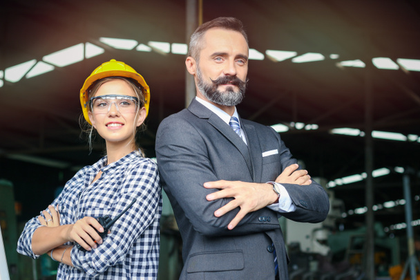 Portrét mladé krásné průmyslové inženýr dělnice a podnikatel šéf nosí bezpečnostní přilbu, stojí se zkříženými pažemi, lidé pracují společně ve výrobě továrny  - Fotografie, Obrázek