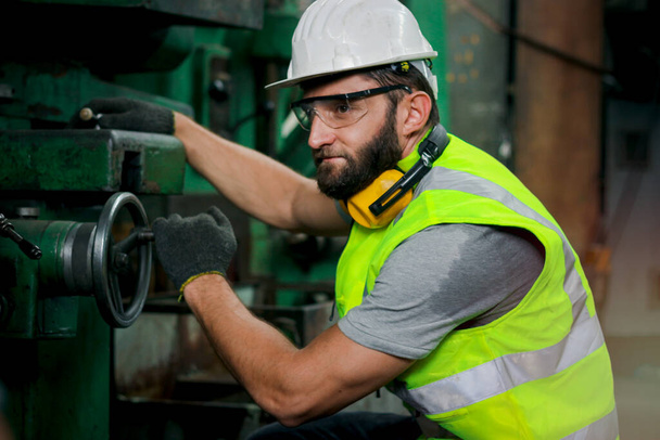 Inżynier przemysłowy noszący kask i bezpieczne okulary pracujący z maszynami w fabryce zakładów produkcyjnych, pracujący z maszyną w koncepcji przemysłowej - Zdjęcie, obraz