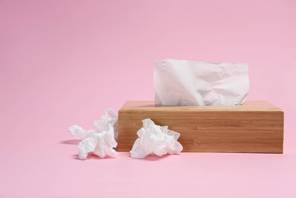 Holder with paper tissues and used crumpled napkins on pink background - Photo, Image