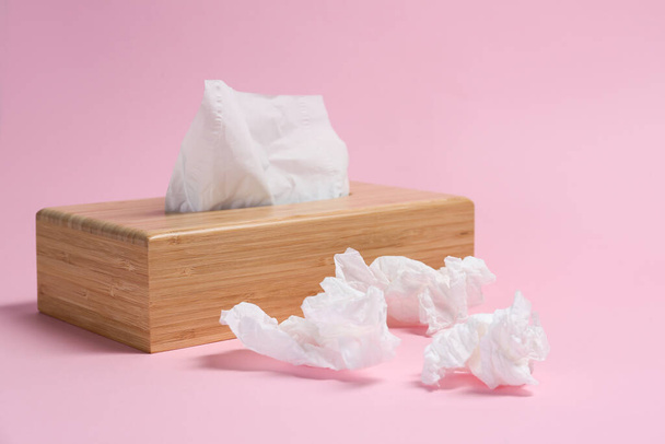 Holder with paper tissues and used crumpled napkins on pink background - Foto, Imagen