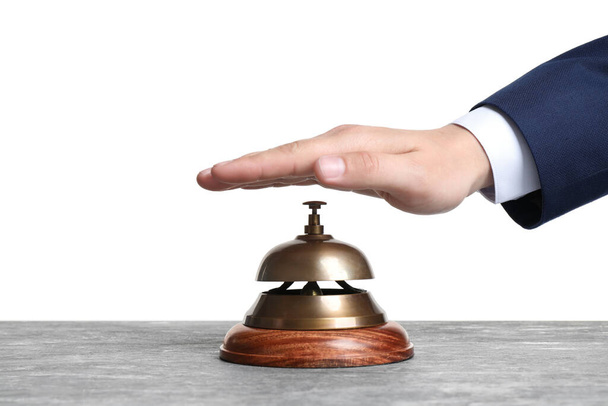 Man ringing hotel service bell at grey stone table - Фото, зображення