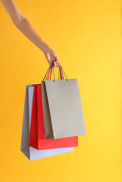Woman with paper shopping bags on yellow background, closeup - Φωτογραφία, εικόνα