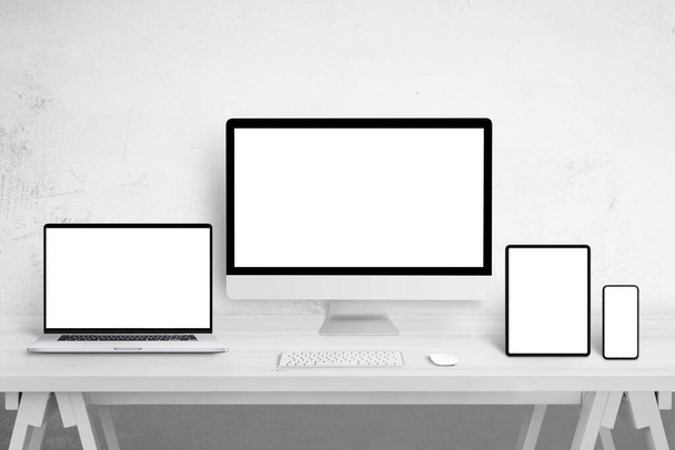 Mockup di dispositivi reattivi per la promozione della progettazione di siti web su display di diverse dimensioni. Schermi bianchi isolati. Tavolo in legno bianco - Foto, immagini