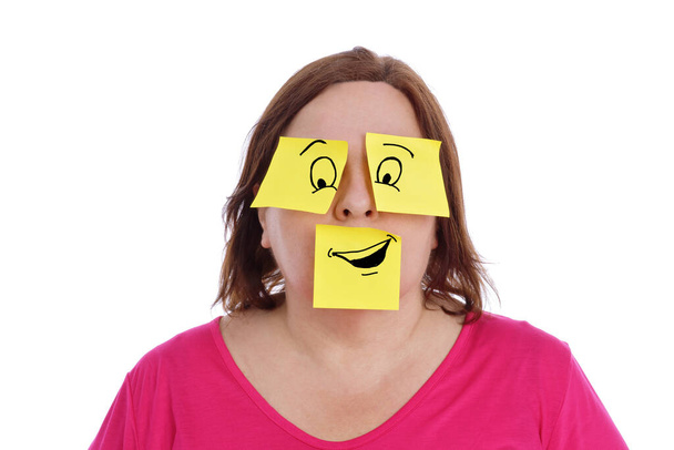 υπέρβαρη γυναίκα που έχει κολλώδεις σημειώσεις κολλημένες στα μάτια και το στόμα της κάνοντας μια κωμική έκφραση με σχέδια σε λευκό απομονωμένο φόντο - Φωτογραφία, εικόνα