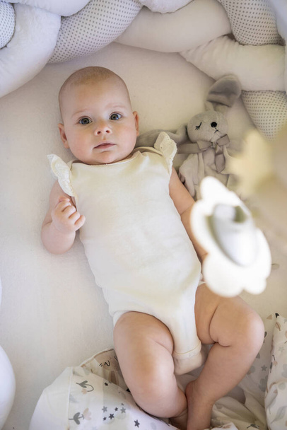 Adorable smiling baby girl with a toy bunny in cot - Fotoğraf, Görsel