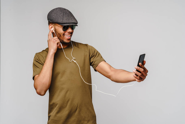 studio shot young african american man listening to music with earphones - Фото, изображение