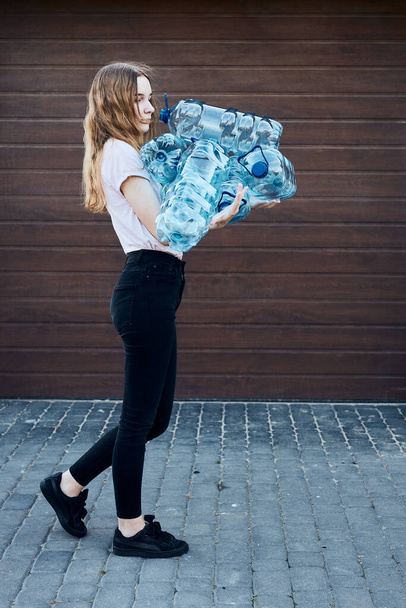Young woman throwing out empty used plastic water bottles into trash bin. Collecting plastic waste to recycling. Concept of plastic pollution and too many plastic waste. Environmental issue - Foto, Imagen
