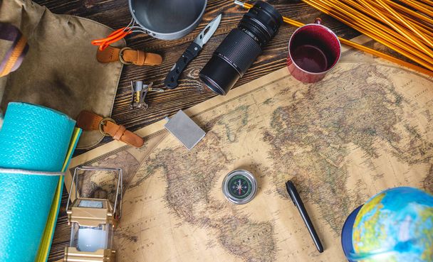 Wanderausrüstung für den Tourismus und eine Weltkarte mit einer Erdkugel auf einem Holztisch. Konzept des Reisens und Entdeckens - Foto, Bild