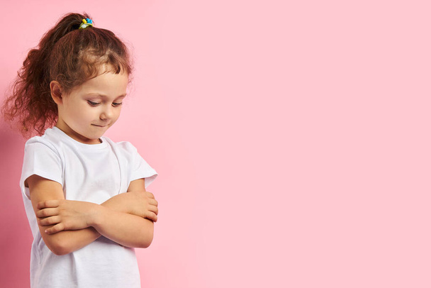 beledigd klein meisje, geïsoleerd op roze achtergrond - Foto, afbeelding