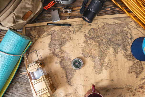 Wanderausrüstung für den Tourismus und eine Weltkarte mit einer Erdkugel auf einem Holztisch. Konzept des Reisens und Entdeckens - Foto, Bild