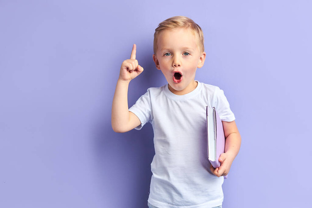 Surprised boy with opened mouth holding notebook - Photo, image