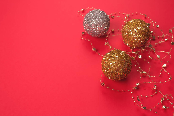 Krásná vánoční a novoroční kompozice se zlatými a stříbrnými vánočními míčky na jasně červeném pozadí. Slavnostní zázemí s copyspace pro váš projekt nebo přáníčko, leták - Fotografie, Obrázek