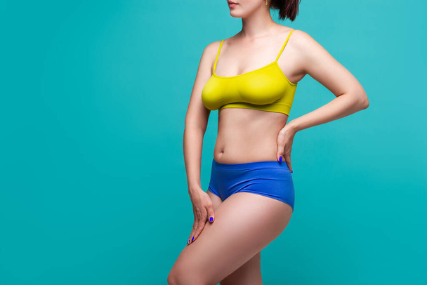 Plus size model in colored underwear on blue background, body positive concept - Foto, Imagen