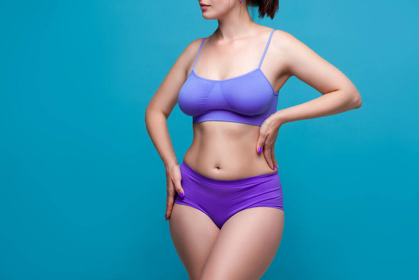 Beauty woman in purple underwear with big natural breasts on blue background, body care concept - Φωτογραφία, εικόνα