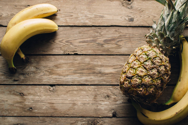 Žlutý banán a ananas na dřevěné podlaze. Obkličte prostor. Ovoce pozadí. - Fotografie, Obrázek