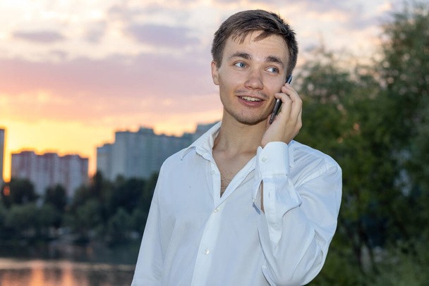 Portrait of a young business man in a white shirt speaks on the phone. - Photo, image