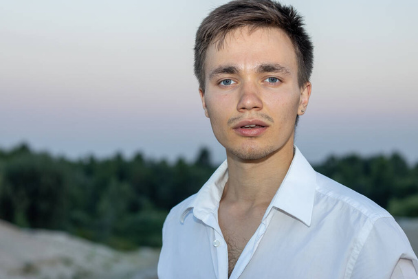 Portrait of a handsome man in a white shirt on nature background. - Fotografie, Obrázek