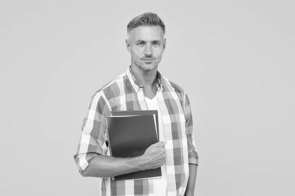 man with folder yellow background. Businessman hold book for notes. guy has notepad for writing. handsome school or university teacher. adult man student holding notebooks. Inspired to work hard - Foto, Imagen
