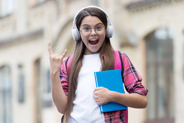 Technology rocks. Happy kid make horns sign. Small girl wear headphones in casual style. English school. New technology. Educational technology. Foreign language education. Online course. Modern life - Photo, image