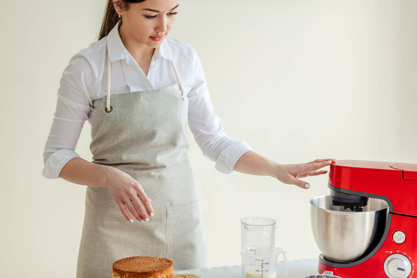 pretty girl working with a blender to make cream for cake - Foto, imagen
