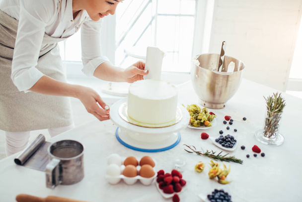 perfect smooth. chef holding a bench scraper vertically agains the cake - Photo, Image
