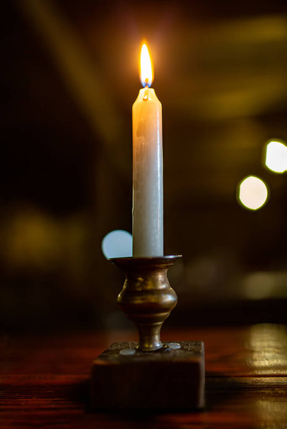Llama de vela. Vela ardiente sobre un fondo oscuro en un candelero antiguo. Luz de vela. - Foto, Imagen