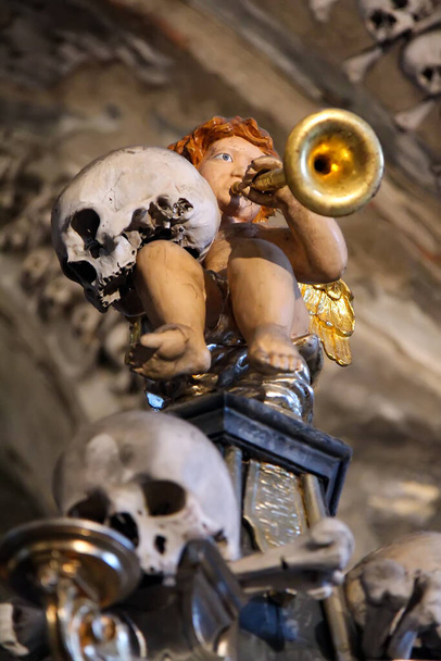 A halál angyala 1278 éve. Egy angyal egy kisgyerek alakjában egy hálóban és por ül a koponyák talapzatán. A halál fogalma és a Halloween ünnepe. Kutna Hora Sedlec Ossuary-tól. - Fotó, kép