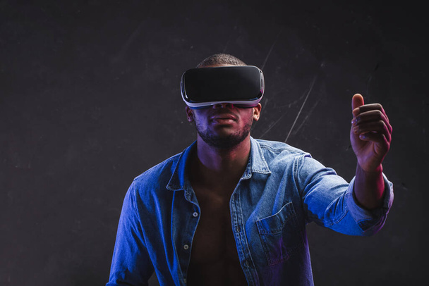 African man wearing virtual reality goggles isolated on dark purple background - Fotografie, Obrázek