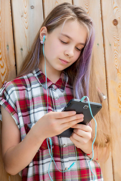 The girl reads a message on a mobile phone. Children and gadgets concept. Communication with friends. - Φωτογραφία, εικόνα