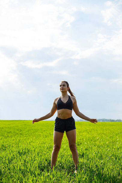 Morning workout. Healthy lifestyle concept. Young attractive woman in sportswear makes stretching her hand before training on the nature at dawn. Muscle warming - Fotó, kép