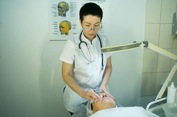 Uma visita a um esteticista. O médico esteticista prepara o rosto do paciente para o procedimento - carboxiterapia. A fase preparatória é a lavagem
. - Foto, Imagem
