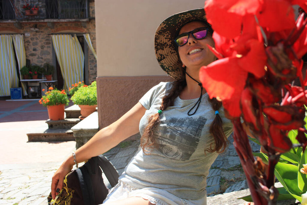dobrodruh dívka mezi květinami a kamennými zdmi na letní dovolenou ve středověké vesnici - Fotografie, Obrázek